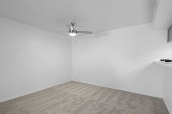 A room with a ceiling fan and carpeted floor.